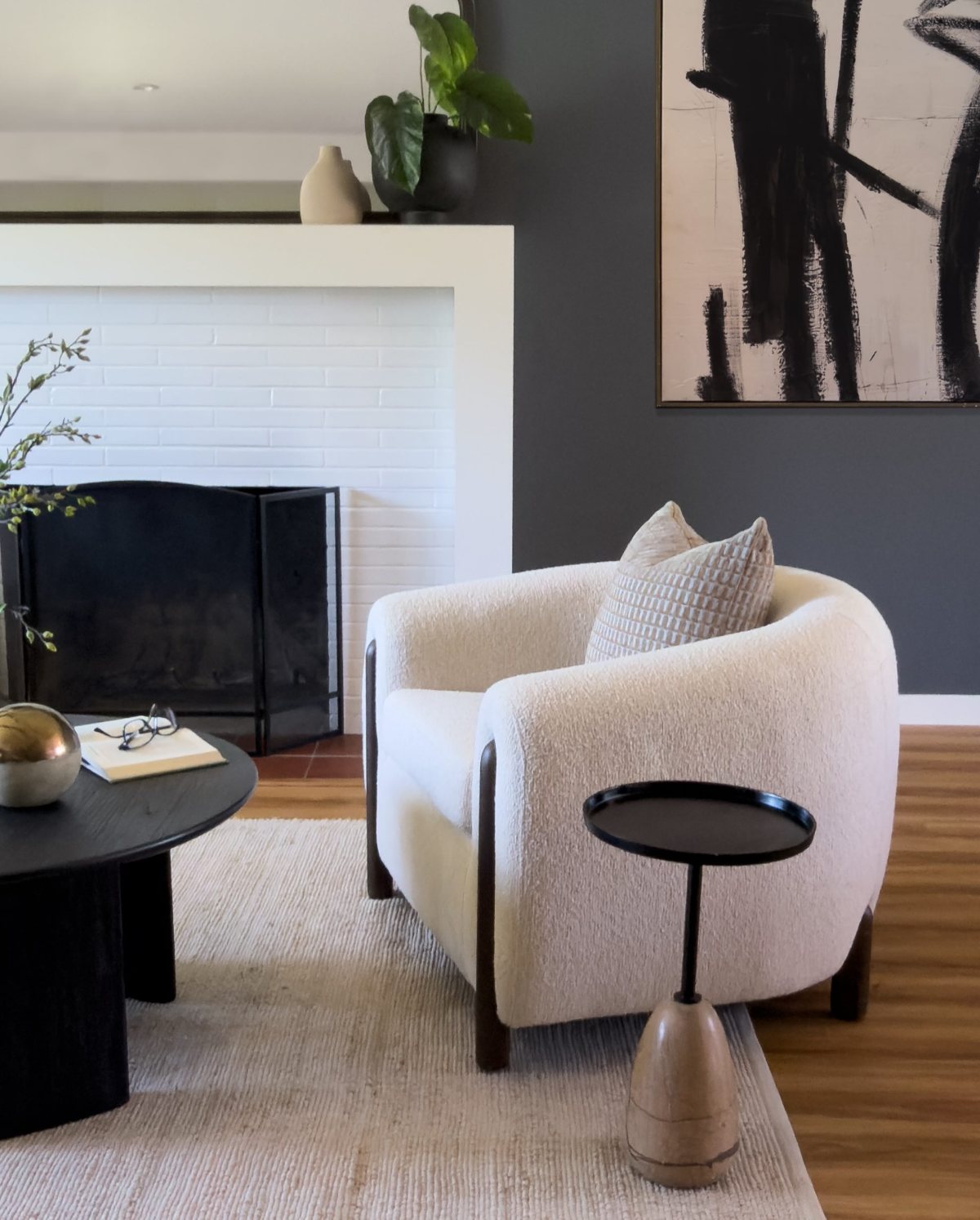 Staged living room with bouclé armchair and painted brick fireplace, San Carlos