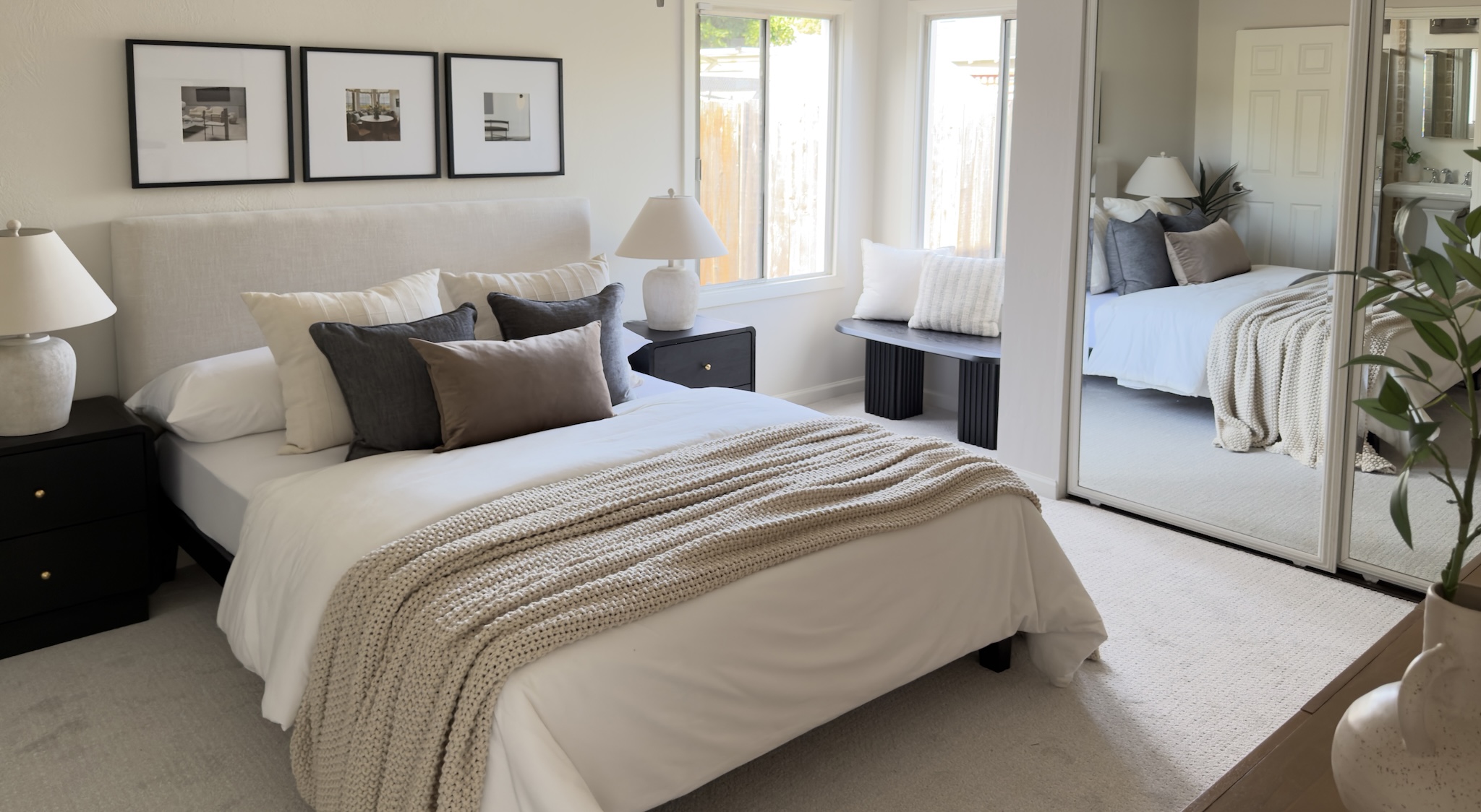 Primary bedroom with framed prints and knit throw