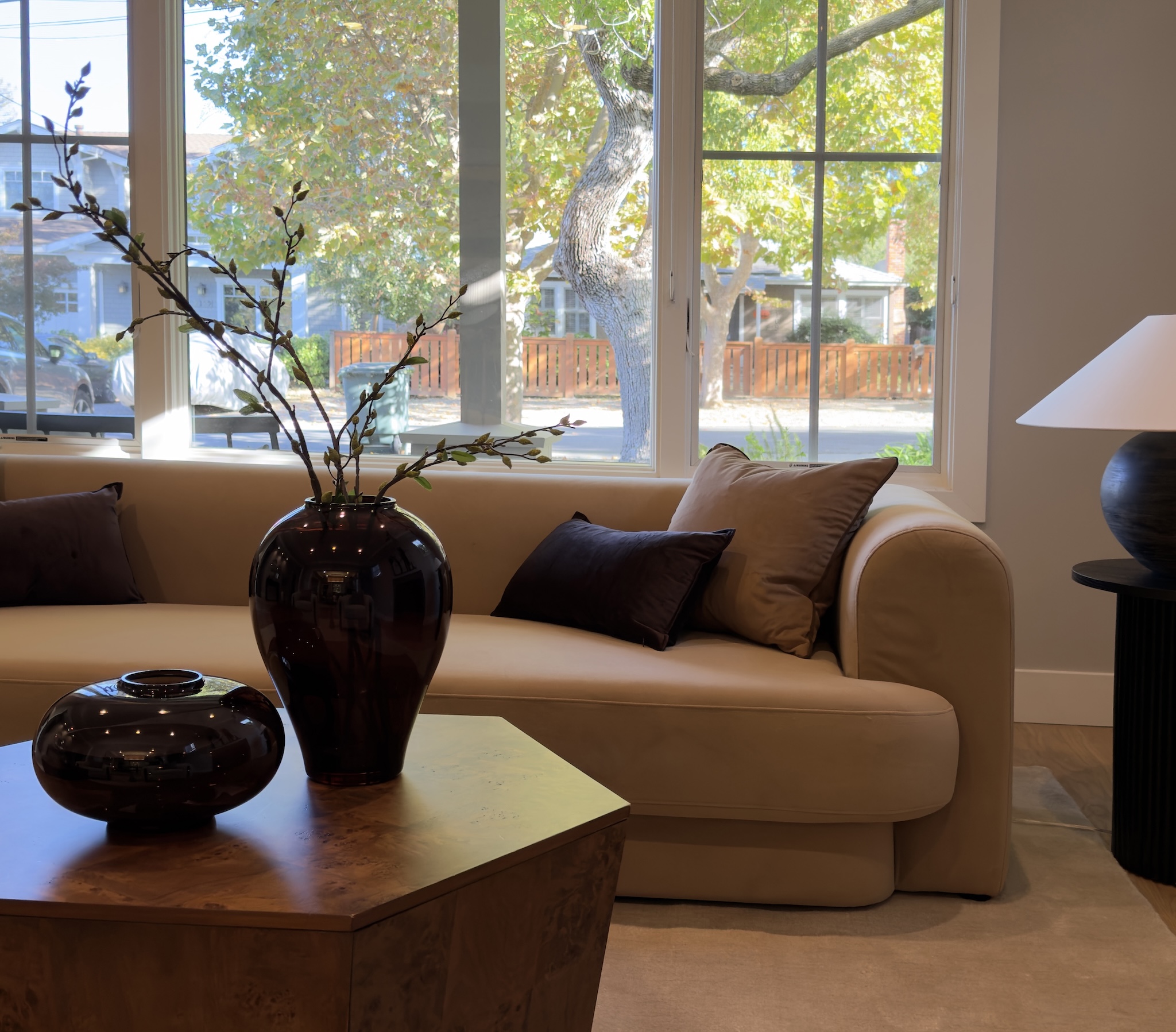 Living room with camel sofa, dark vase and garden windows