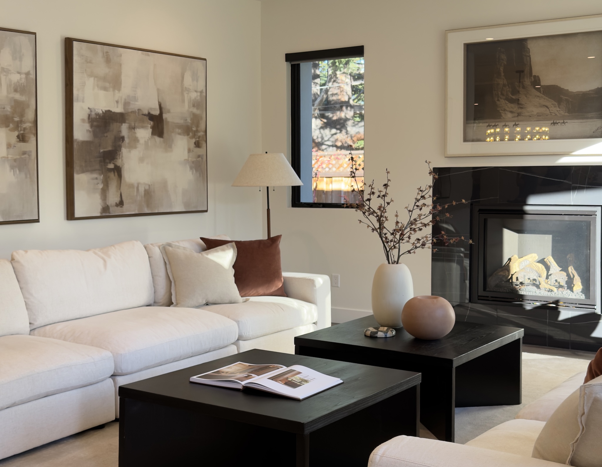 Staged living room with white sectional, black coffee table and fireplace