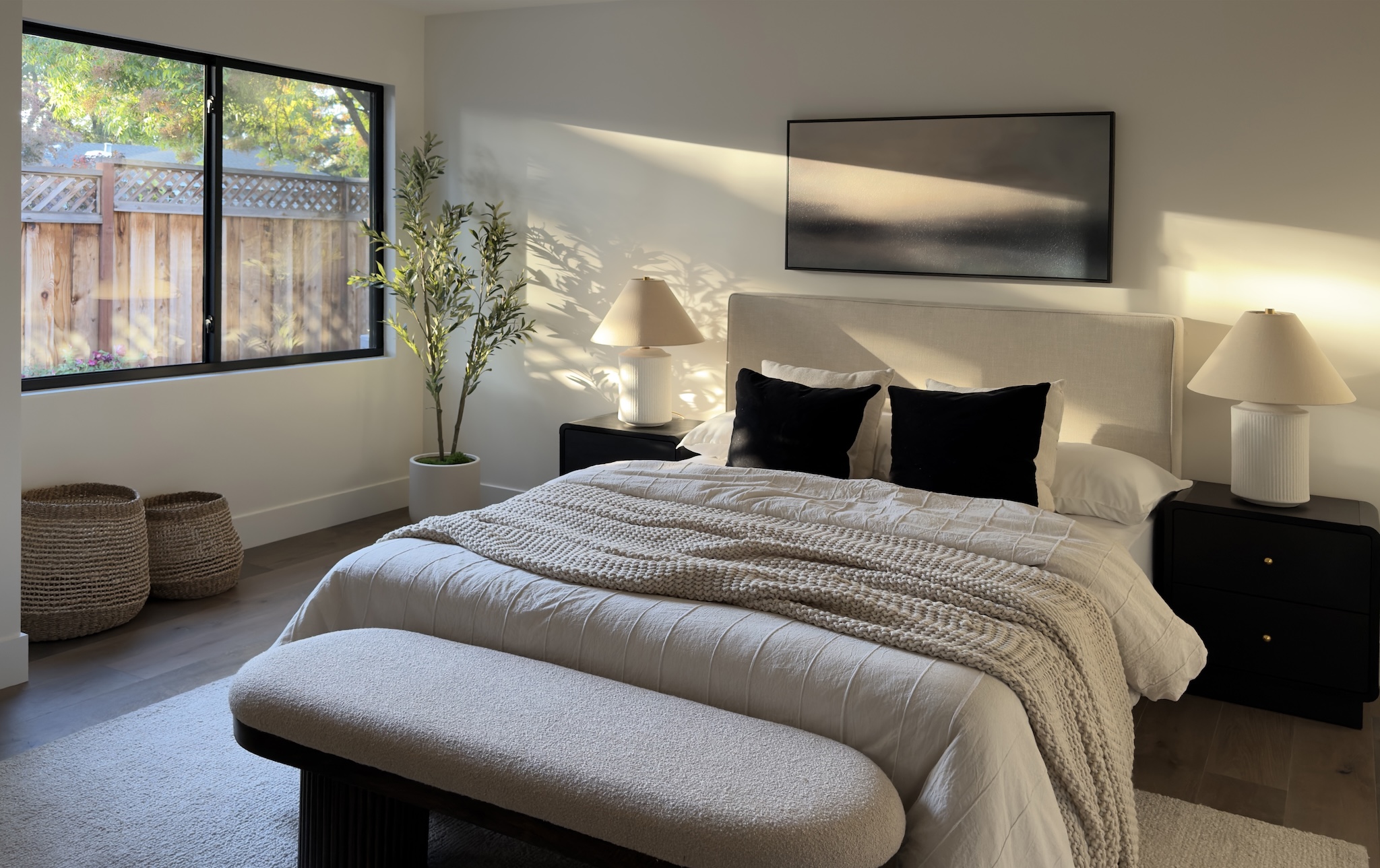 Staged bedroom with bench and black nightstands