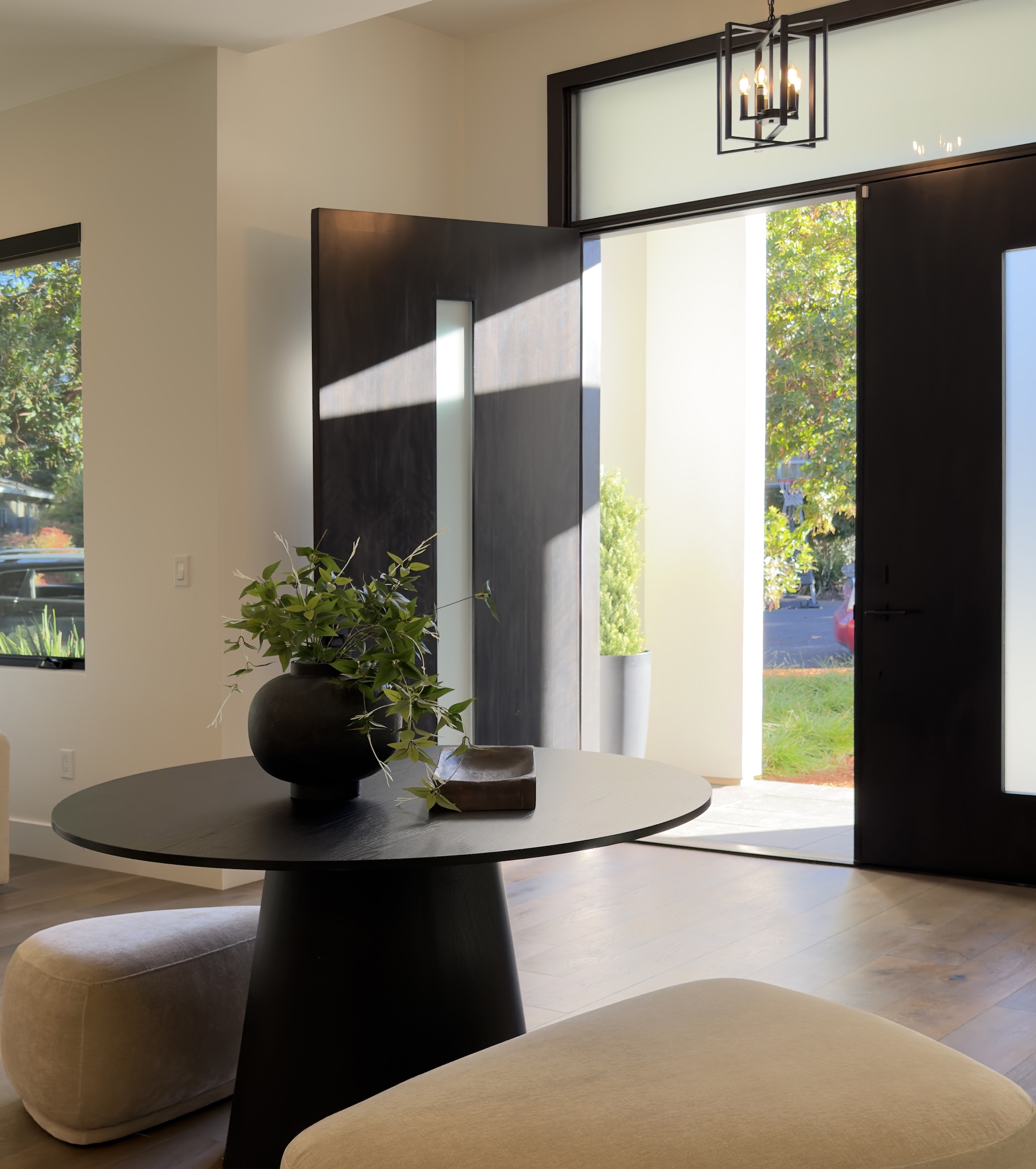 Entry with round black table, olive branches and open pivot door
